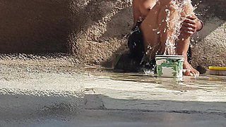 Indian sister-in-law is bathing in the open courtyard of the house, putting a finger in her burrow and rubbing the body, sister-in-law is washing the bathroom.