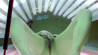 Brunette plays with her pussy in solarium