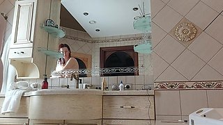 A Charming Woman Is Preening in the Bathroom in Front of a Mirror