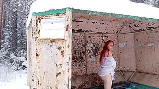 A redheaded girl is playing with her body at a public bus stop in winter!
